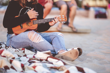 A closeup focus shot of a woman playing ukulele at the beach