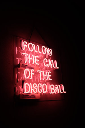 A "Follow the call of the disco ball" neon sign with red led lightsの写真素材