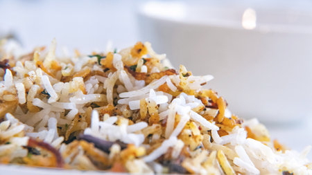 A closeup shot of delicious Indian Hyderabadi biryani with a white blurry background