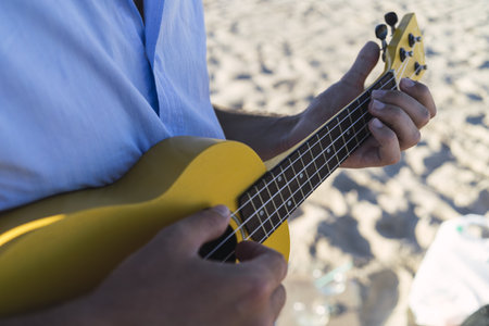 A young male playing the ukulele at the beach San Fernando, Cadiz, Andaluciaの写真素材