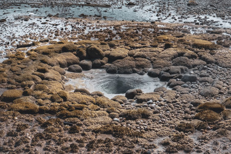 A high angle shot of a hole in the ground surrounded by rocks and pebblesの写真素材