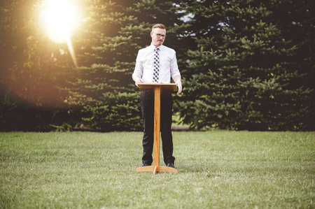 A young male standing near a wooden speech stand- perfect for oratory, speech, lecturing concepts