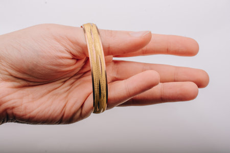 A closeup shot of a hand putting on a gold bracelet