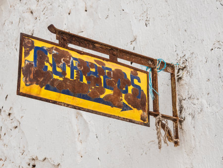 A low angle shot of a rusty yellow and blue sign on a white wallの写真素材