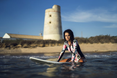 A view of a European female sitting on a surfboard