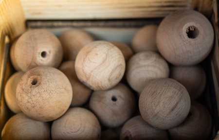 A closeup of round wooden beads in a box under the lightsの写真素材