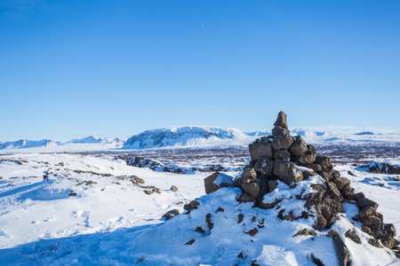 A landscape of a field covered in rocks and snow under the sunlight in Icelandの写真素材