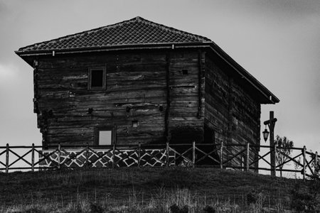 An old rustic wooden house on top of a hill in black and whiteの写真素材