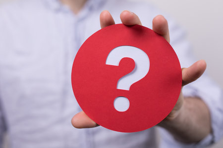 A man holding a round red sign with white question sign on itの写真素材