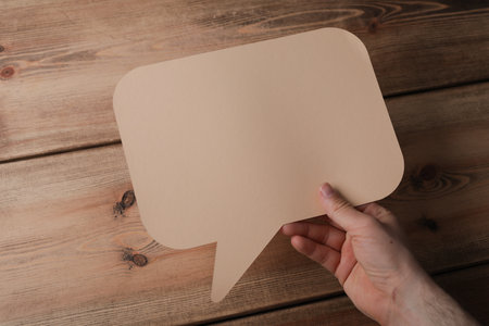 A high angle closeup shot of a man holding a beige message icon on a wooden background