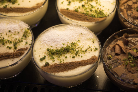 A closeup view of vanilla and chocolate desserts with chocolate, cinnamon, and nuts as toppingsの写真素材