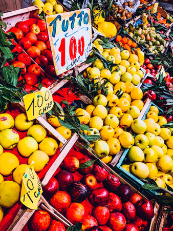 A closeup shot of yellow and red apples in wooden boxes in the street market in Italyの写真素材