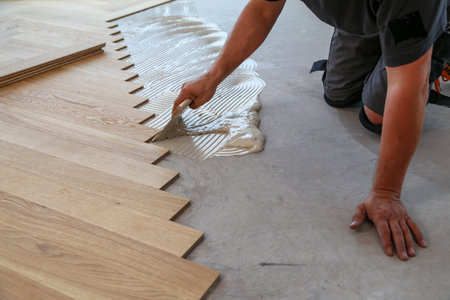 A male worker installing a wooden laminate flooring on his kneesの写真素材