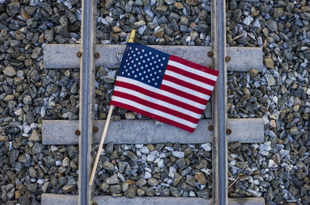 A high angle closeup shot of the flag of the USA on the train rails