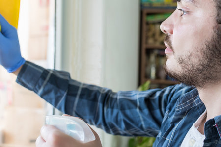 A young male with gloves cleaning window glass