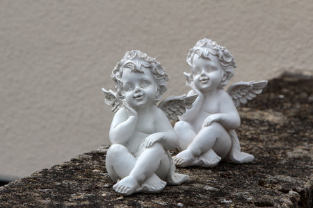 A closeup shot of two miniature angels on a stone wallの写真素材