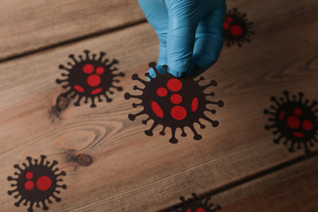 A closeup shot of a person in medical blue gloves holding coronavirus cellsの写真素材