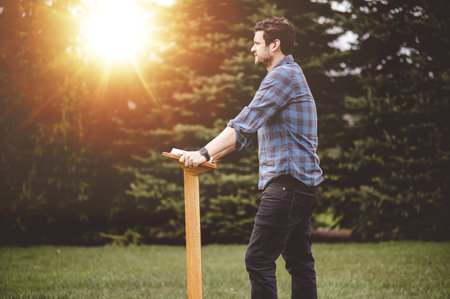A religious person giving a speech at the tribune in a park with bright sunlight in the background