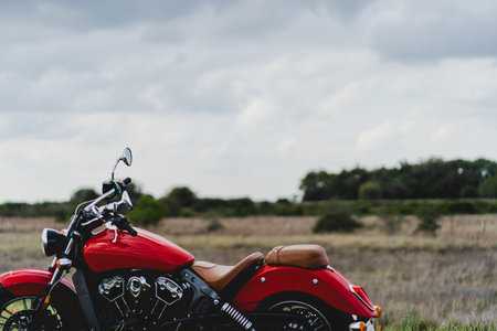A closeup shot of a red motorcycle with a field in the blurry backgroundの写真素材