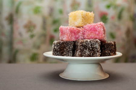 A closeup shot of colourful Australian dessert Lamingtons stacked and served on a cake standの写真素材