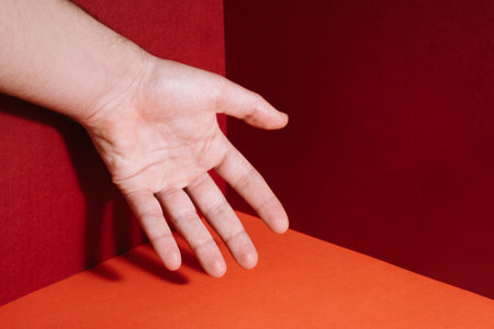 A closeup shot of a hand on red and orange corner backgroundの写真素材