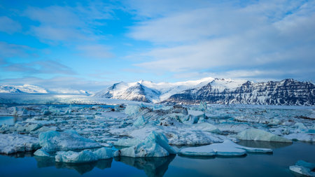 A landscape of hills and a lake covered in ice under the sunlight in Iceland