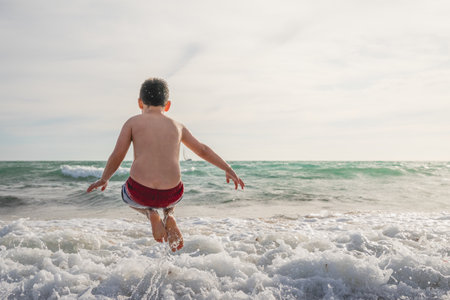 The back view of a caucasian boy jumping on the eaves of the sea