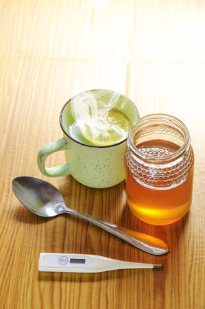 A closeup shot of infusion, honey, lemon, and thermometer - the remedy for the symptoms of the flu or COVID-19の写真素材