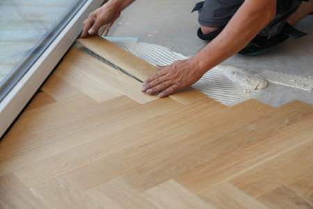 A closeup of a worker installing wooden laminate flooringの写真素材