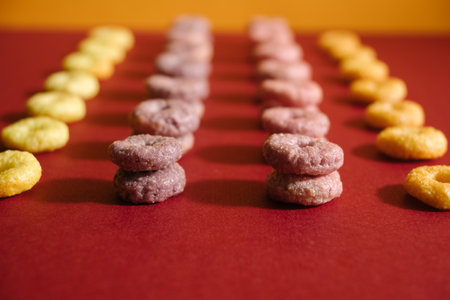 A selective focus shot of yellow, pink and purple ancient glass beads on red backgroundの写真素材