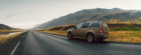 A view of a car on a road surrounded with hills in Iceland captured on a cloudy dayの写真素材