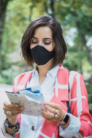 A woman holding a map and wearing a protective mask