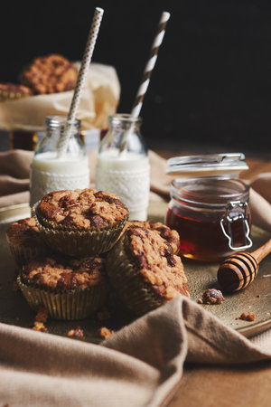 A vertical shot of chocolate muffins with honey and milk