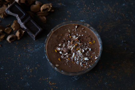 A high angle shot of a delicious chocolate mousse with nuts on the table