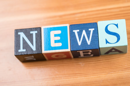 A high angle shot of [NEWS] written with letter cubes on the table under the lightsの写真素材