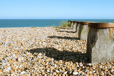 A beautiful view of pebble beach with groynes at daytimeの写真素材