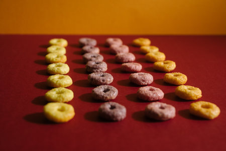 A selective focus shot of yellow, pink and purple ancient glass beads on red backgroundの写真素材