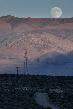 An amazing shot of a mountain landscape during a sunrise with a big moonの写真素材