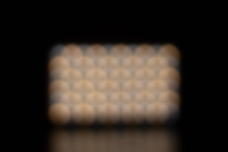 White and orange bokeh background with a reflection in a dark area.