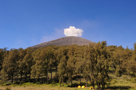 A view of Mount Semeru  in Indonesia, puffing volcanic clouds against clear blue skyの写真素材