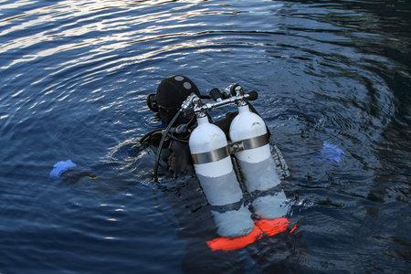 A scuba diver plunges into the dark water of a deep lake