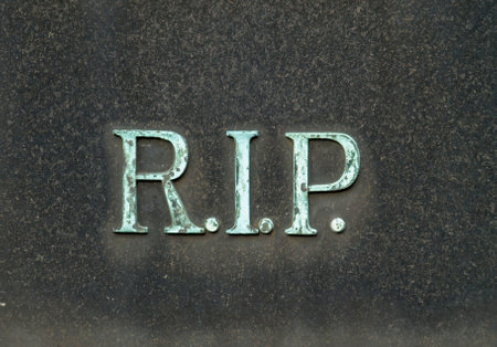 A tombstone with  bronze letters  R.I.P on itの写真素材