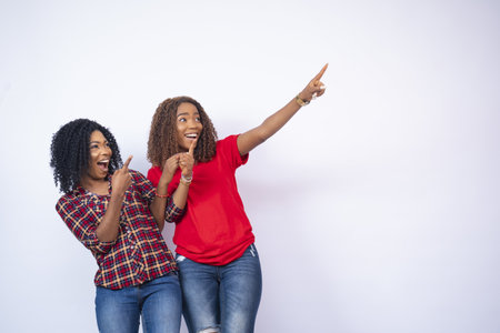 The two beautiful black woman pointing at something happy and excitedの写真素材