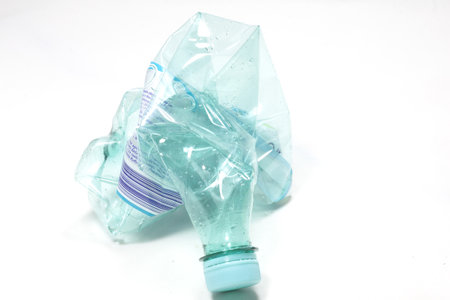A closeup view of a crashed empty water bottle isolated on a white surface
