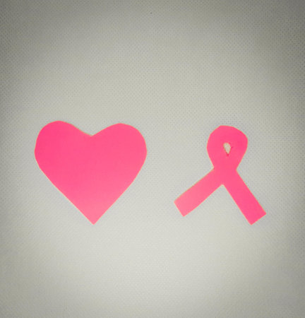 A top view of a pink paper heart and ribbon for breast cancer awarenessの写真素材