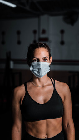 A vertical shot of an athletic female wearing a sanitary mask - concept of the new normalの写真素材