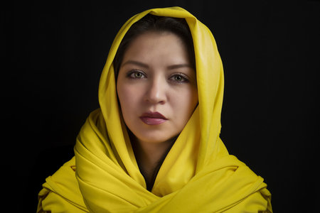 A closeup portrait of a beautiful Caucasian woman with a scarf on her head  isolated on a black backgroundの写真素材