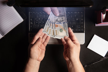 A conceptual picture of a man taking cash from the laptopの写真素材