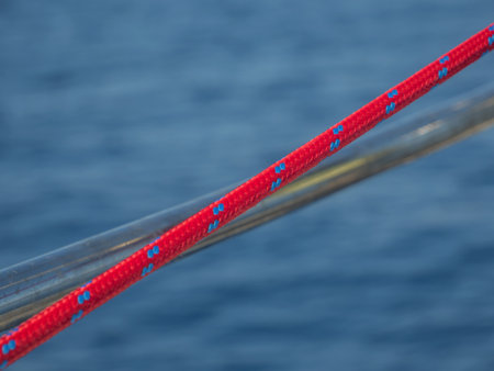 A soft focus of a red boat rope stretched across a boat against blue watersの写真素材