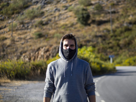 A young European male walking down a road with a face mask - the new normal after Covid-19